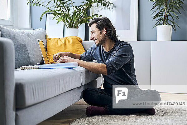 Männlicher Student lernt  während er zu Hause einen Laptop benutzt