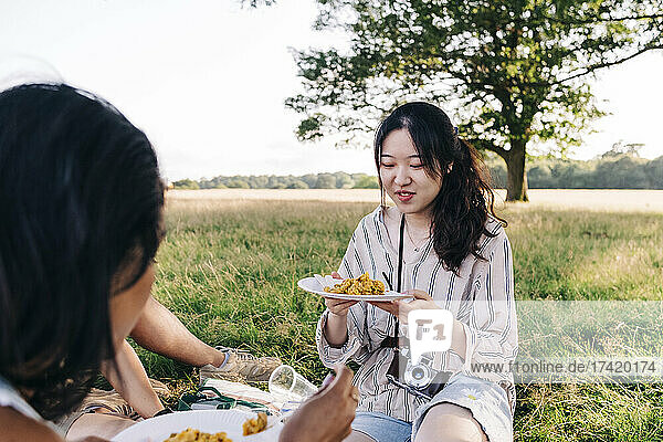 Friends eating food during picnic in park