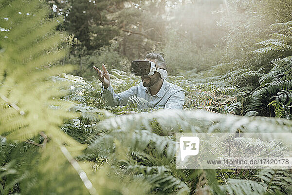 Man gesturing while using virtual reality headset in forest
