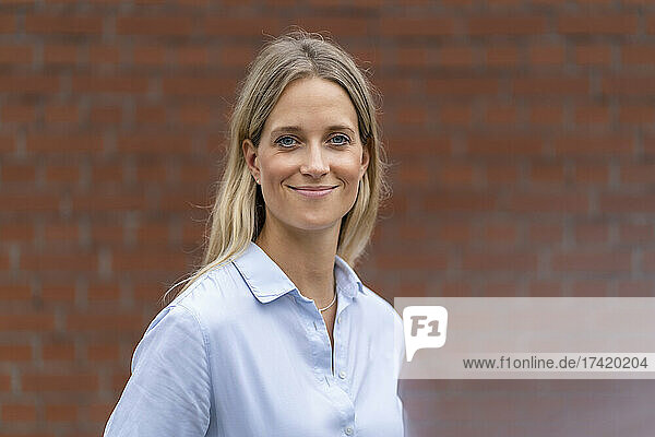 Smiling female business professional in front of wall