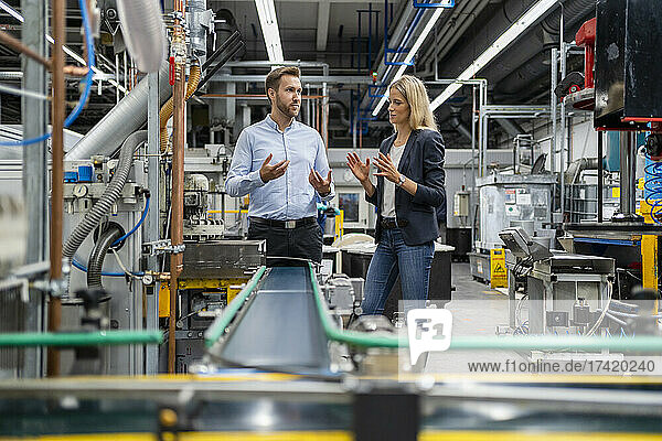 Business professionals having discussion while standing at production line