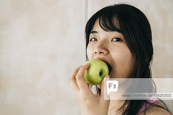 Woman eating apple at home