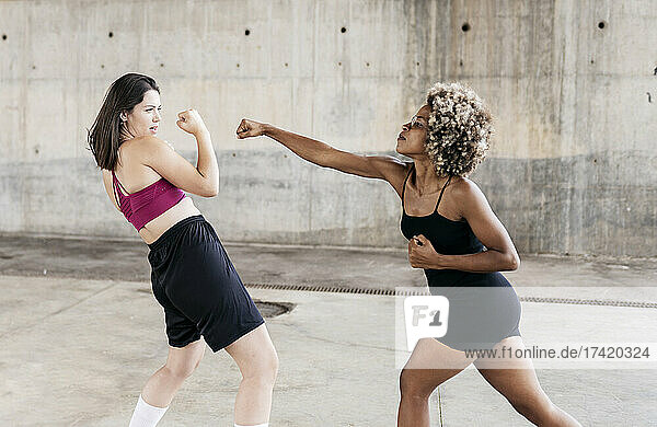 Multi-ethnic female friends punching while boxing