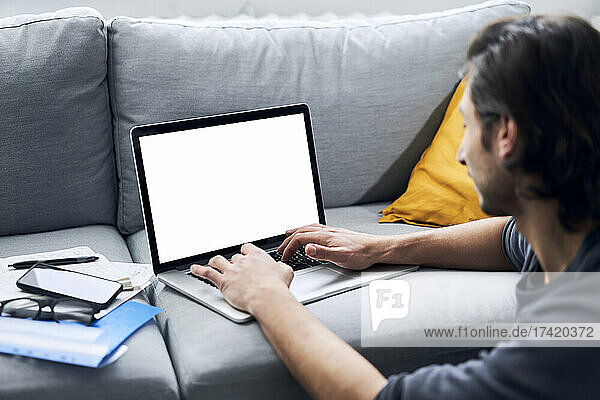 Geschäftsmann tippt auf Laptop  während er zu Hause arbeitet