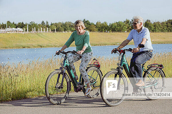Couple riding bicycle together on road during sunny day