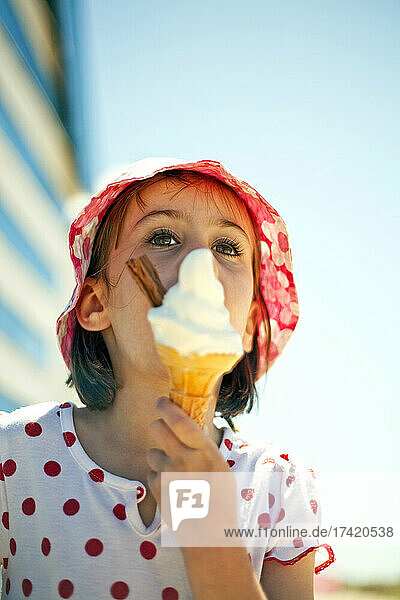 Girl looking away while eating ice cream in sunlight