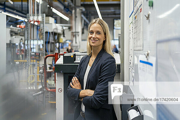 Young female manager with arms crossed standing at industry
