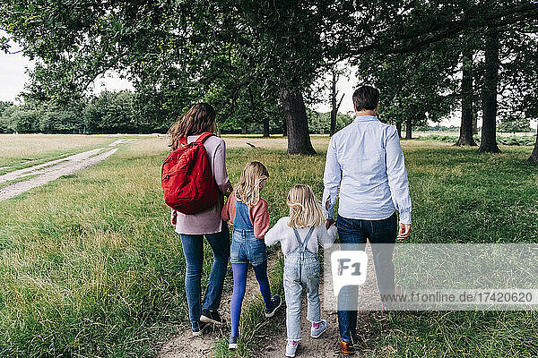 Daughters holding hands of parents while walking at park