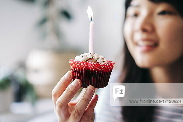 Frau hält Cupcake mit Kerze zu Hause