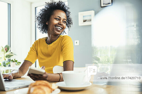 Happy businesswoman looking away while working at home office