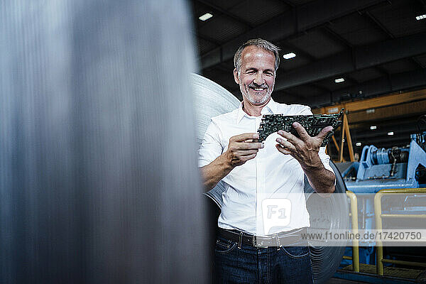 Smiling businessman checking equipment in metal industry
