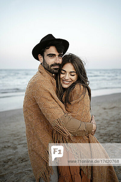 Lächelnder Mann umarmt Frau am Strand