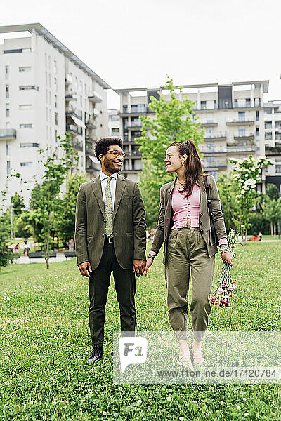Business couple looking at each other while standing on meadow