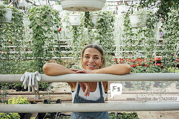 Smiling mature female farmer leaning on railing