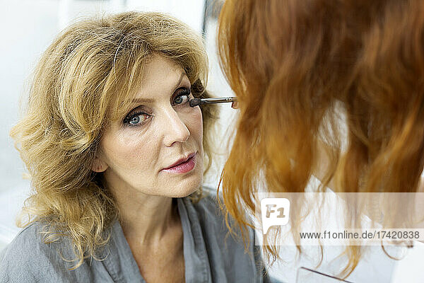 Female artist applying make-up to senior woman
