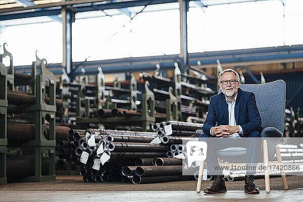 Male managing director sitting on armchair in factory