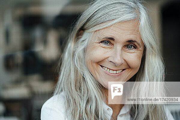 Lächelnde reife Frau mit grauen Haaren im Café