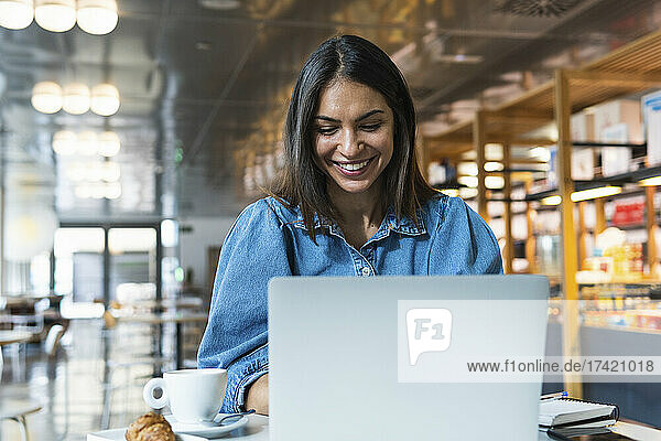 Lächelnde Geschäftsfrau  die im Café am Laptop arbeitet