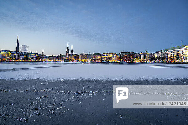 Germany  Hamburg  Frozen surface of Inner Alster Lake at dawn with city skyline in background