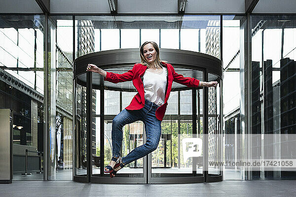Carefree businesswoman with arms outstretched jumping at entrance