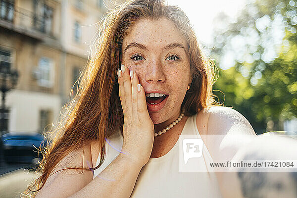 Surprised young woman with freckles taking selfie