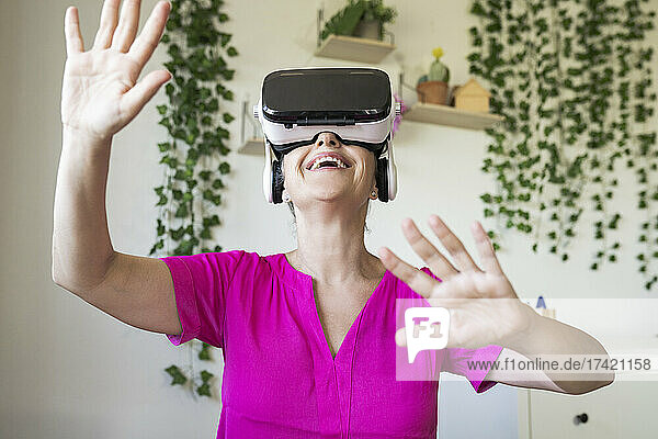 Happy mature woman wearing virtual reality headset at home