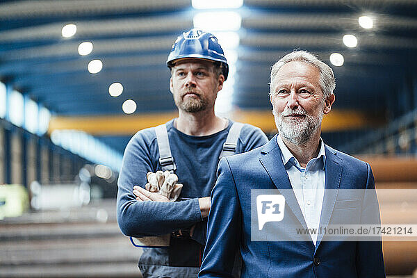 Businessman standing with warehouse worker in industry