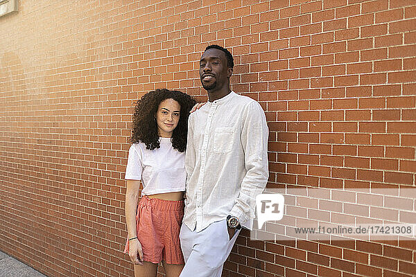 Man and woman standing in front of brick wall