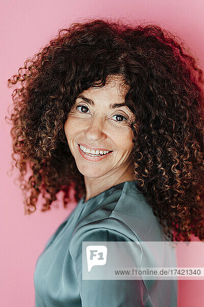 Mature businesswoman smiling against pink background