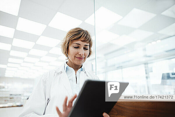 Smiling female medical professional using digital tablet at pharmacy