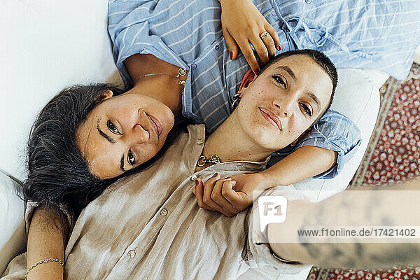 Lächelndes lesbisches Paar macht ein Selfie  während es zu Hause auf dem Sofa liegt