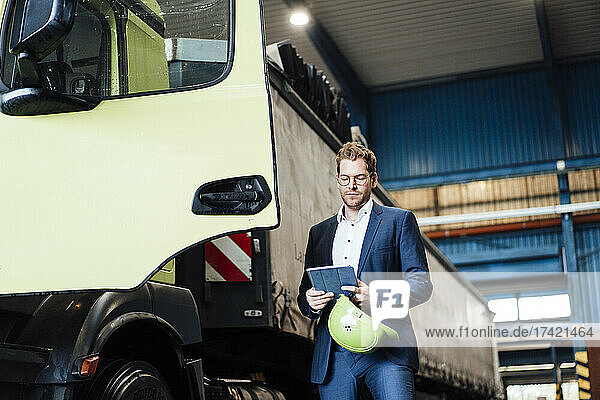Male manager using digital tablet while standing by truck