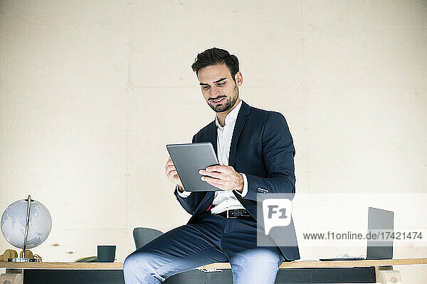 Junger männlicher Berufstätiger nutzt digitales Tablet  während er am Schreibtisch im Büro sitzt