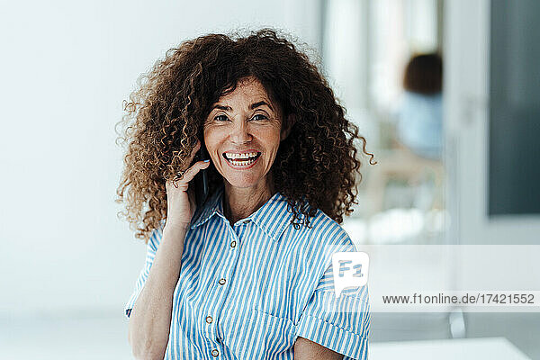 Smiling businesswoman talking on mobile phone at office