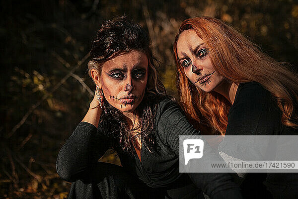 Friends with Halloween make-up and costume sitting in forest