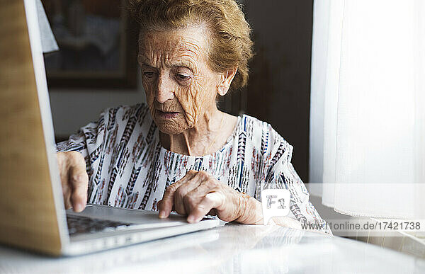 Senior woman with short hair using laptop at home