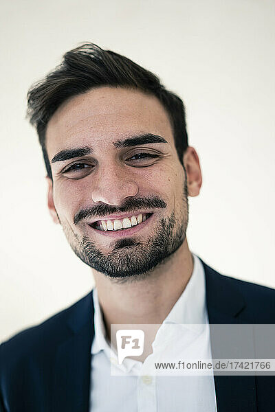 Happy young businessman with hair stubble in office