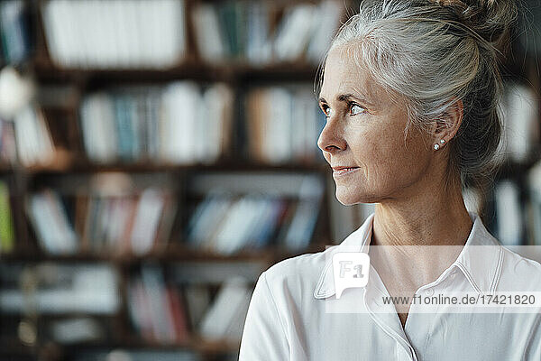 Businesswoman with gray hair in front of bookshelf at cafe