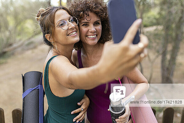 Smiling friends taking selfie through smart phone