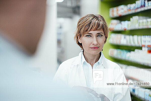 Blond female pharmacist standing at medical store