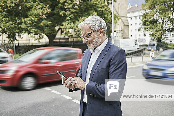 Bearded businessman using mobile phone on road