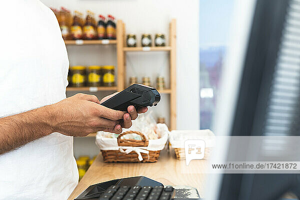 Male store owner using credit card reader at counter