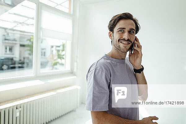 Lächelnder Mann  der zu Hause mit dem Handy telefoniert