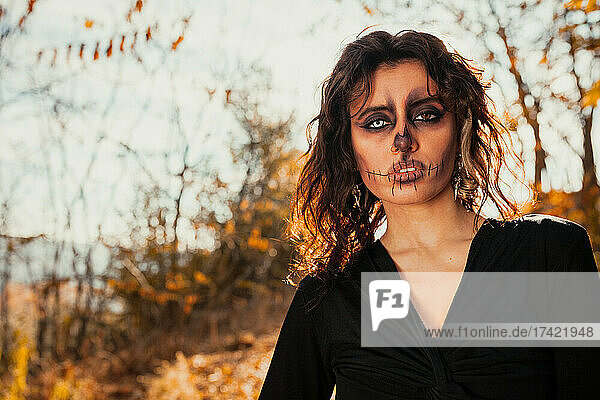 Young woman with spooky Halloween make-up in forest