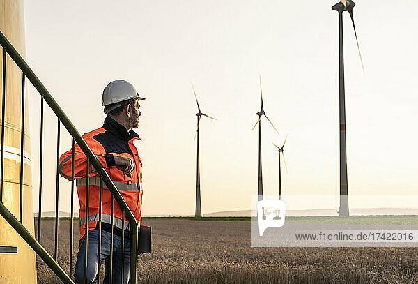 Male inspector at wind turbines during sunset