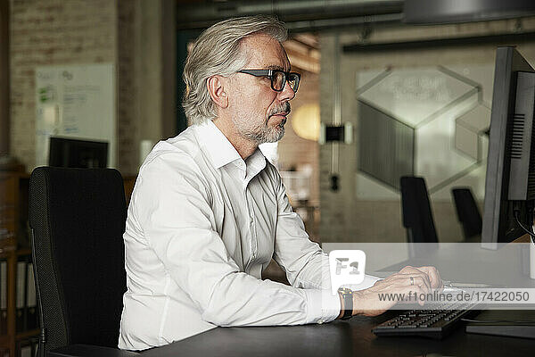 Businessman with gray hair working on computer in office