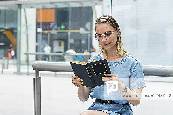 Blond businesswoman with eyeglasses reading book