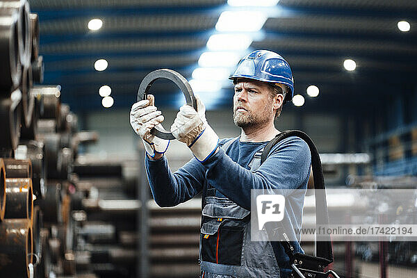 Male inspector with hardhat checking steel equipment in factory