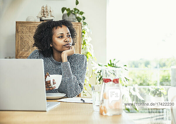 Businesswoman with coffee cup contemplating at home office
