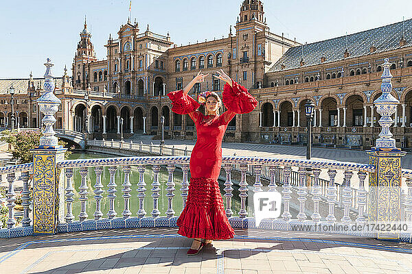 Flamenco-Künstlerin tanzt an einem sonnigen Tag mit erhobenen Händen auf der Plaza De Espana in Sevilla  Spanien